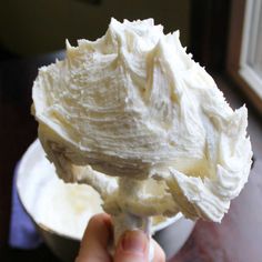 a person holding a spoon full of whipped cream