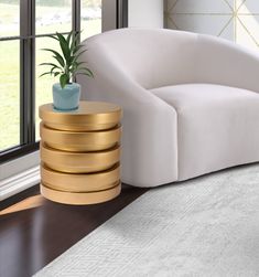 a white couch sitting in front of a window next to a table with a potted plant on it