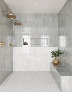 a white tiled bathroom with gold fixtures and a plant in the corner on the counter