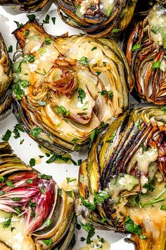 roasted artichokes with garlic sauce and parsley on top, in a white plate