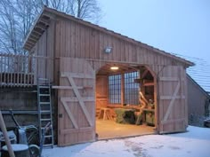 an open garage door in the middle of a snow covered yard with ladders on it