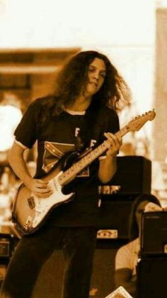 a man with long hair playing an electric guitar