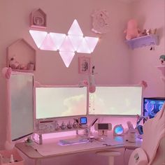 two computer monitors sitting on top of a desk in front of a pink wall and ceiling