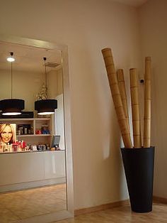 a tall vase with bamboo sticks sticking out of it's sides in front of a mirror