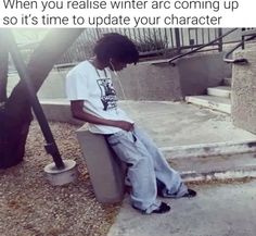 a young man sitting on top of a cement block next to stairs and looking at his cell phone