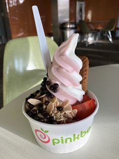 an ice cream sundae with chocolate chips and strawberries in a cup on a table