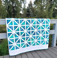 a blue and white quilt sitting on top of a wooden deck