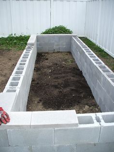 an unfinished garden bed in the middle of a yard with dirt and grass growing around it