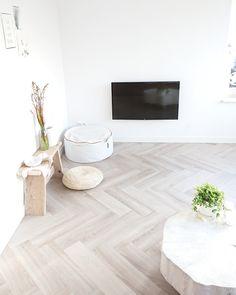 a living room with white walls and wood flooring is shown in front of a flat screen tv