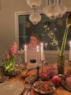 a woman sitting at a table with food and candles in front of her