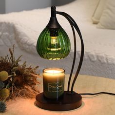 a green glass lamp sitting on top of a wooden table next to a candle holder