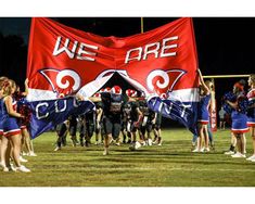 a group of cheerleaders standing in front of a red and white banner with the words we are surrounded by other cheerleaders