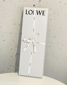 a white box sitting on top of a toilet with a ribbon tied around the lid