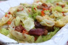 a salad with lettuce, carrots and bacon in a white paper container