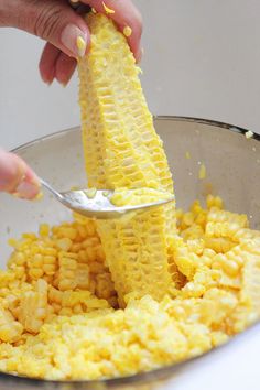 a person is scooping corn into a bowl