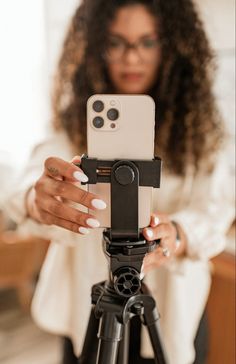 a woman taking a photo with her cell phone on a tripod in the living room