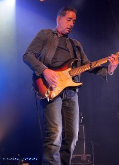 a man standing on top of a stage holding a guitar