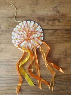 a kite made out of yarn and ribbons on a wooden table with string attached to it