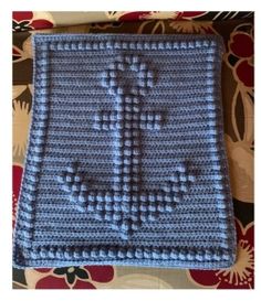 a blue and white crocheted blanket with a cross on it