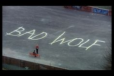 the words bad wolf are written in chalk on the ground next to a red bench