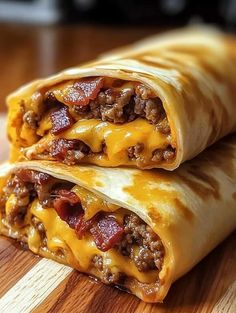 two burritos sitting on top of a wooden cutting board