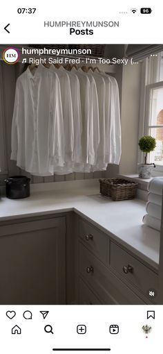 a white kitchen counter top next to a window with clothes hanging on the rack above it