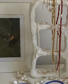 there is a white sculpture with pearls on it next to a framed photo and necklaces