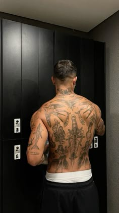 a man with tattoos on his back standing in front of lockers