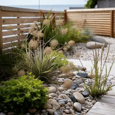 a wooden bench sitting next to a gravel and grass covered garden area near the ocean