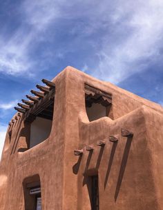 an adobe building with several windows on the side and blue sky in the back ground