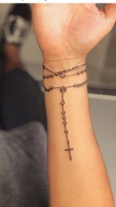 a person with a rosary tattoo on their wrist and the words jesus christ is coming up from