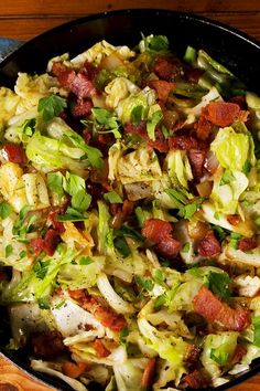 a skillet filled with lots of food on top of a wooden table