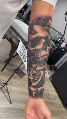 a person with a tattoo on their arm holding a rose and a skull in his hand