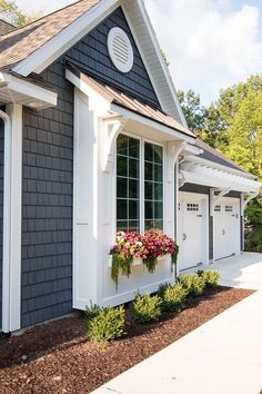 a gray and white house with flowers in the window boxes on the front porch area