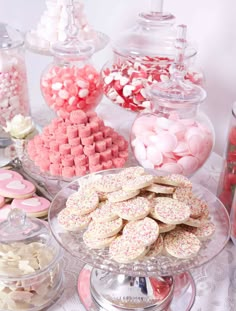 a table topped with lots of different types of cookies and candies on top of glass plates