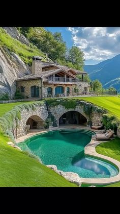 an outdoor swimming pool in the middle of a lush green field with mountains in the background