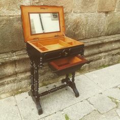 an old fashioned vanity with a mirror on it's stand next to a stone wall