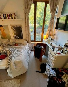 an unmade bed sitting in a bedroom next to a window