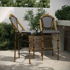 two chairs sitting next to each other in front of a planter filled with plants