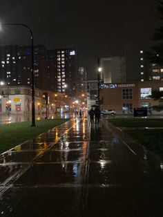 two people walking down the street in the rain at night with their umbrellas open