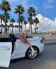 a woman sitting in the back of a white car with her legs up on the hood