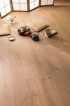 a room with wooden floors and various items on the floor, including teapots