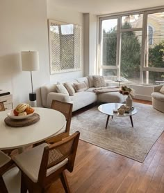 a living room filled with furniture and a white table in front of a large window