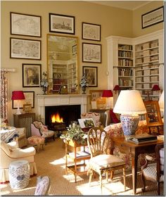 a living room filled with lots of furniture and pictures on the wall above it's fireplace