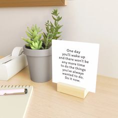 a desk with a notepad, pen and plant on it