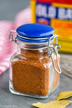 a glass jar filled with spices sitting on top of a table next to a spoon