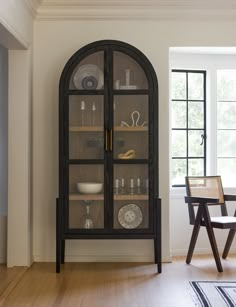 a dining room table and chairs in front of a glass cabinet with dishes on it