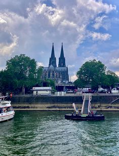 two boats in the water near a large church with spires on it's side