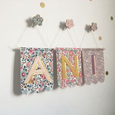 two letters are hanging on the wall with flowers and polka dotes around them that spell out an n