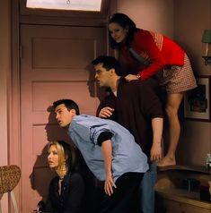 three people standing on top of each other in front of a door with the woman leaning against the man's head